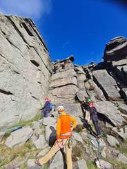 A group of people climbing an outdoor rockface